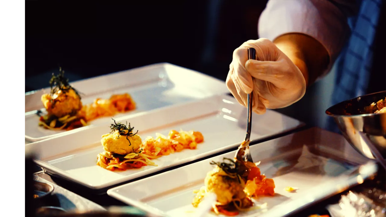 Image of a hand of a chef prepping a dish.