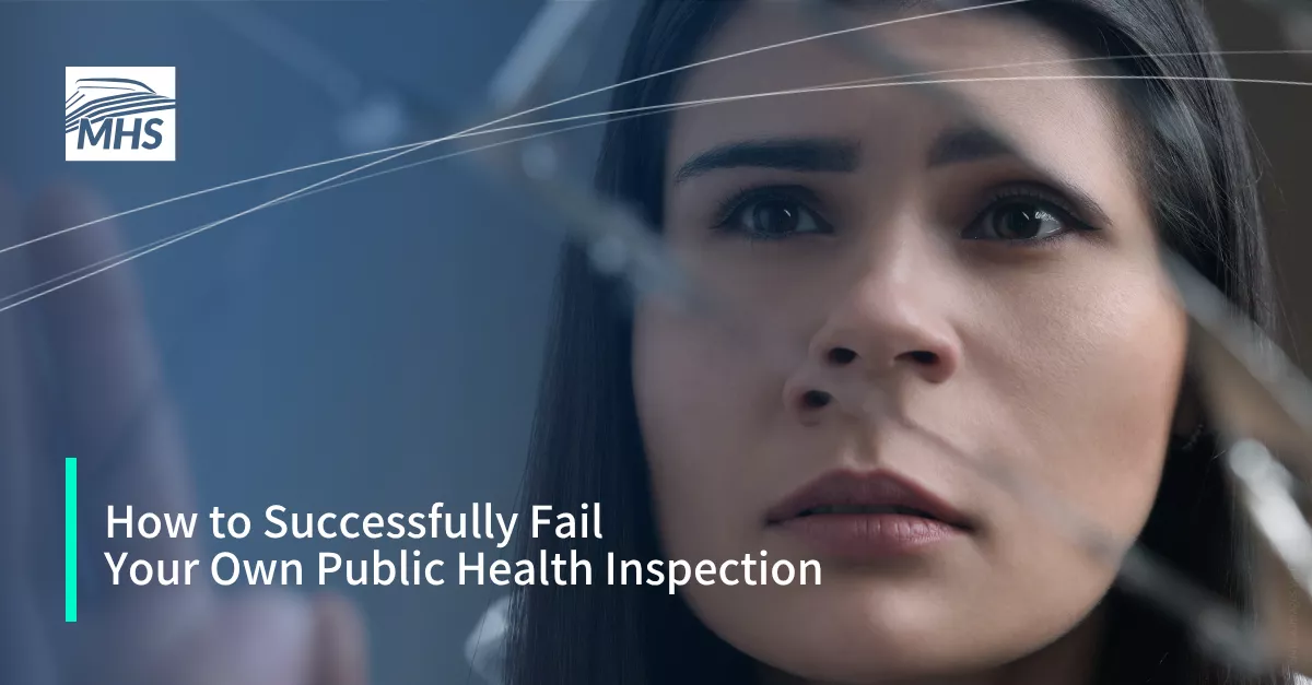 A closeup of a young woman looking at her own reflection in a broken mirror with the words, How to Successfully Fail Your Own Public Health Inspection
