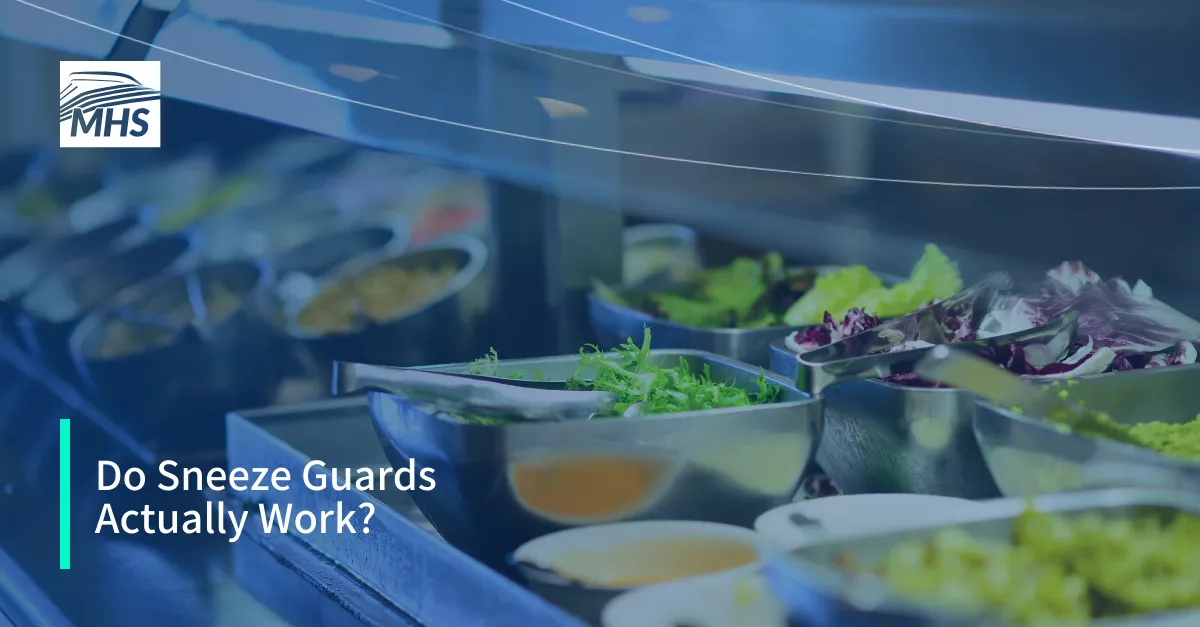 A sneeze guard positioned over a buffet salad line with the words, Do Sneeze Guards Actually Work?